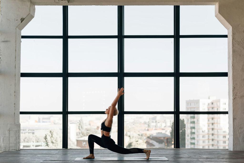 Woman doing yoga in front of huge window | CorePower Yoga