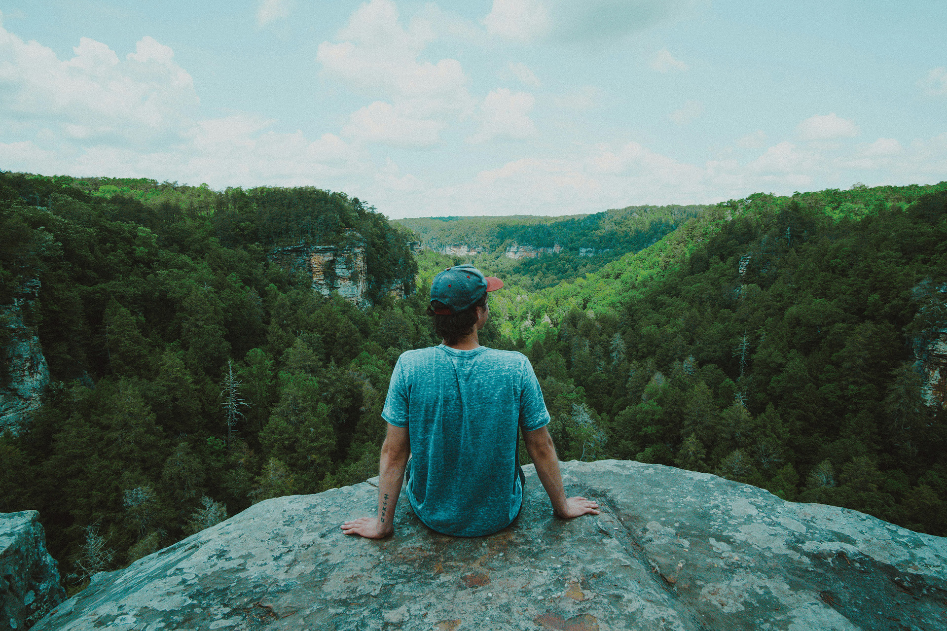 A man sat on a rock observing the natural scene below