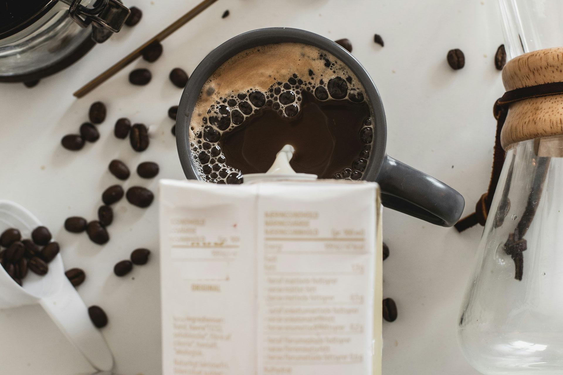 Oat milk being poured into a mug of coffee.