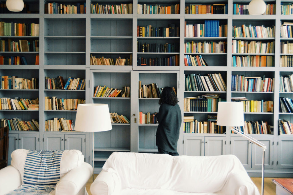 A woman admiring her home bookshelf