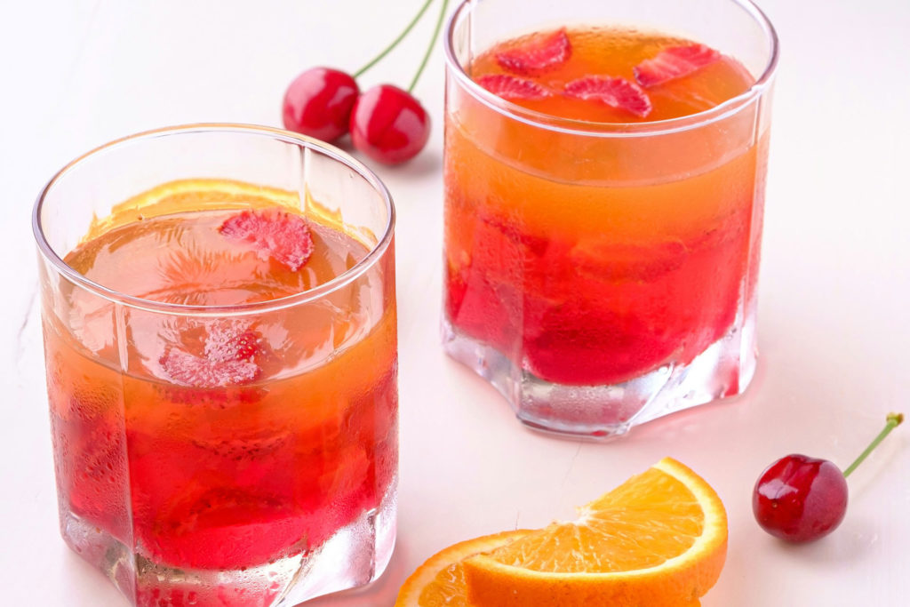 Orange and cherry cocktails in glass tumblers