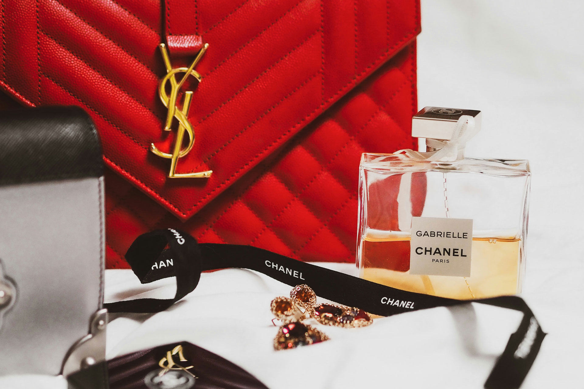 Red YSL bag, Chanel No.5 perfume and a black Chanel ribbon.