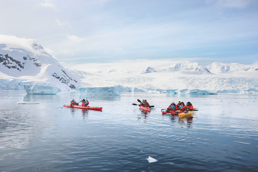 People in kayaks paddle in Antarctica