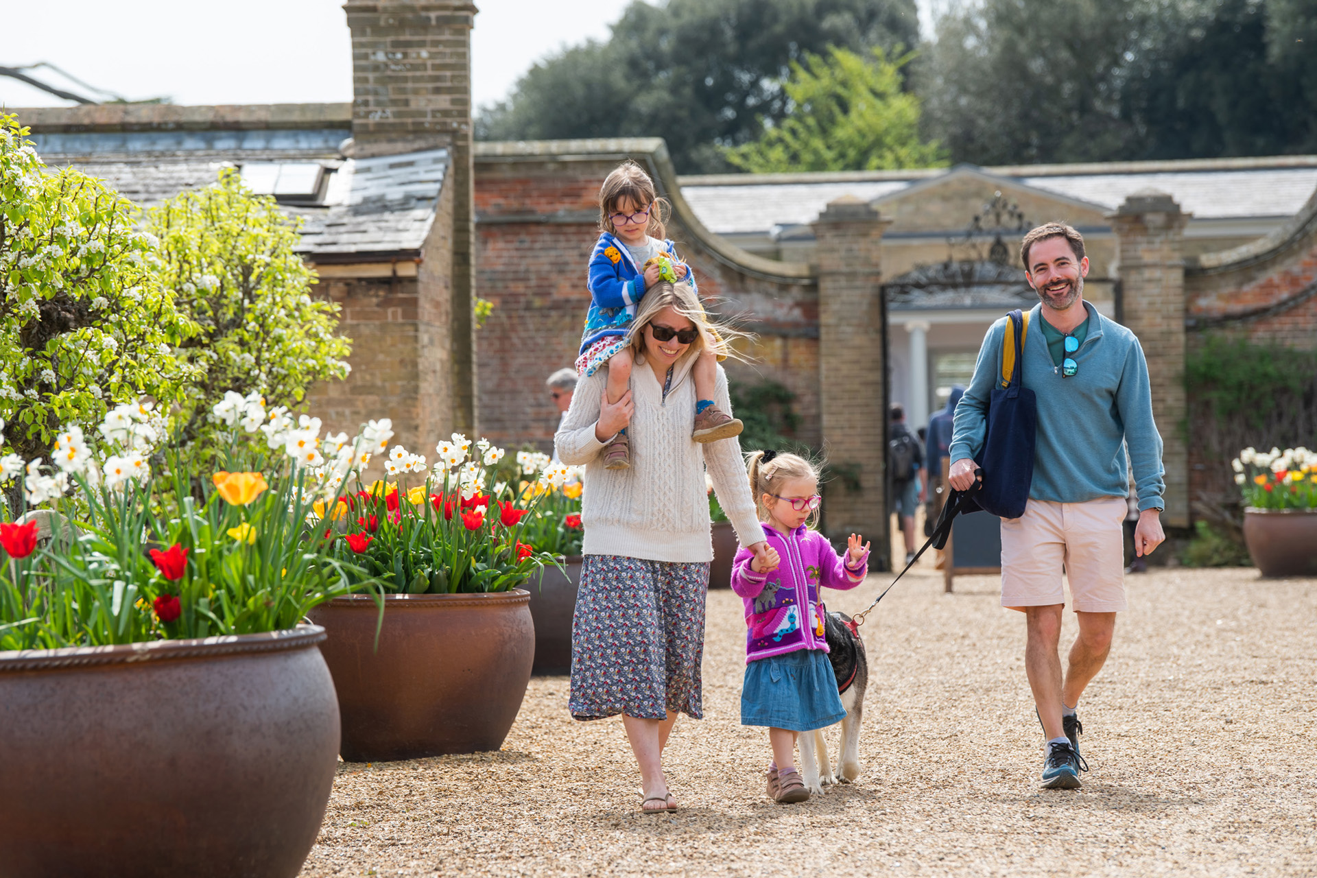 A family walking beside spring flowers at Holkham