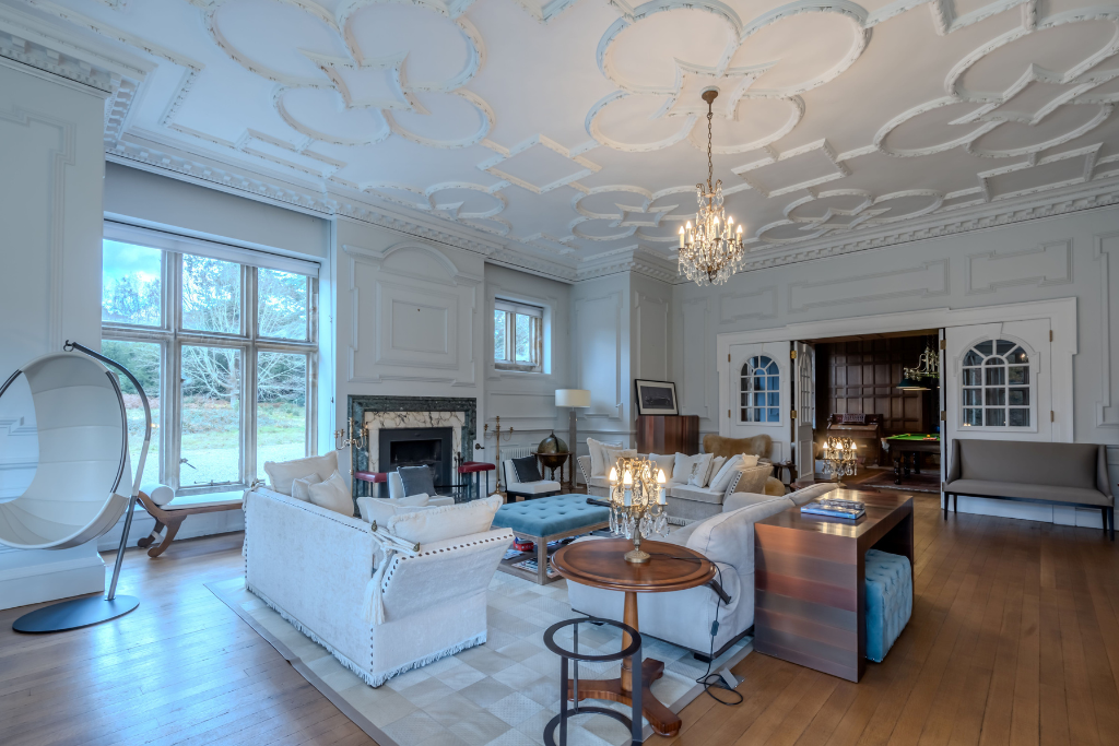 Living room with ceiling cornicing, parquet flooring and white sofas.