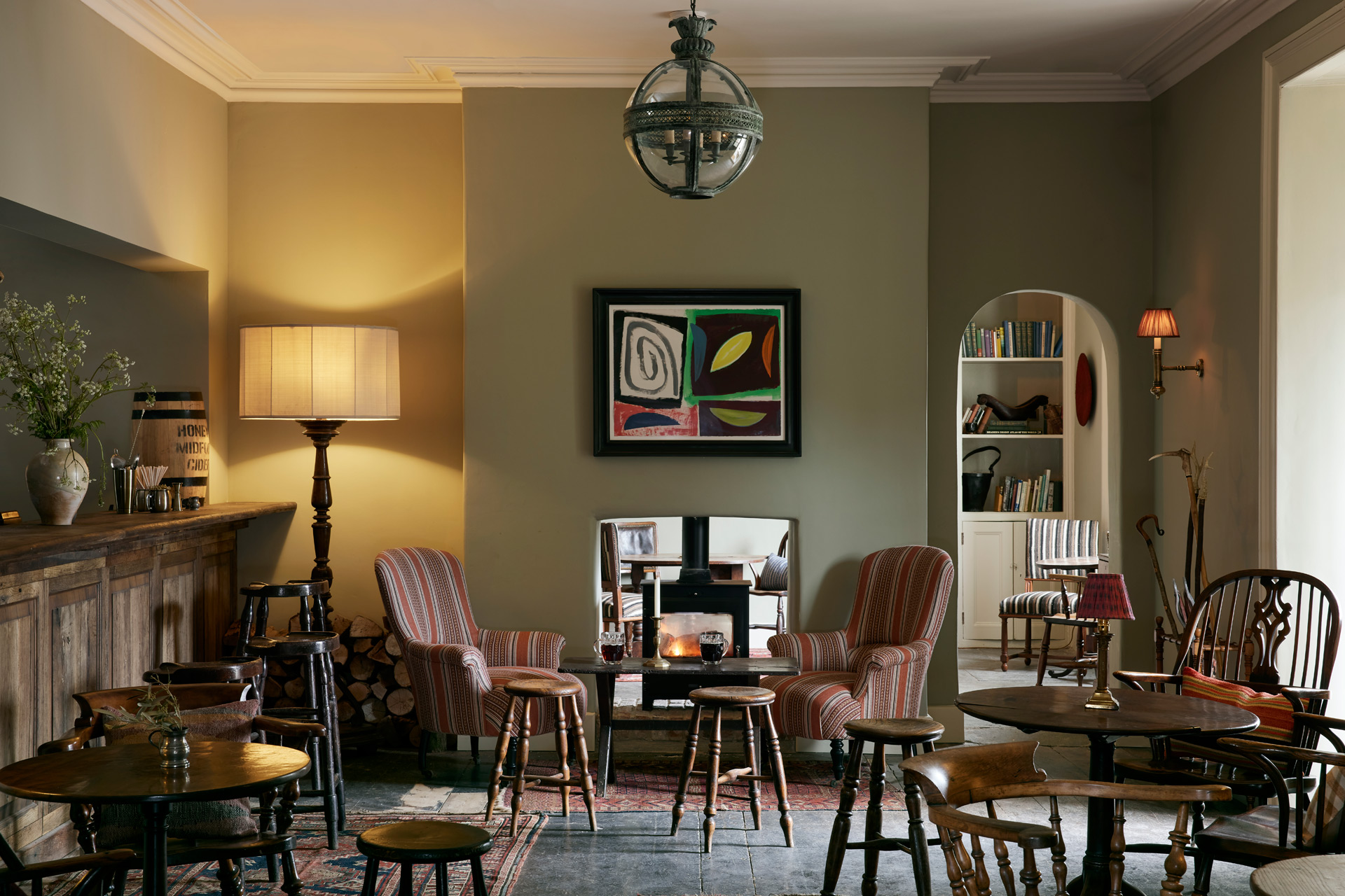 Restaurant with wooden tables, mismatched armchairs and a sage green colour palette.