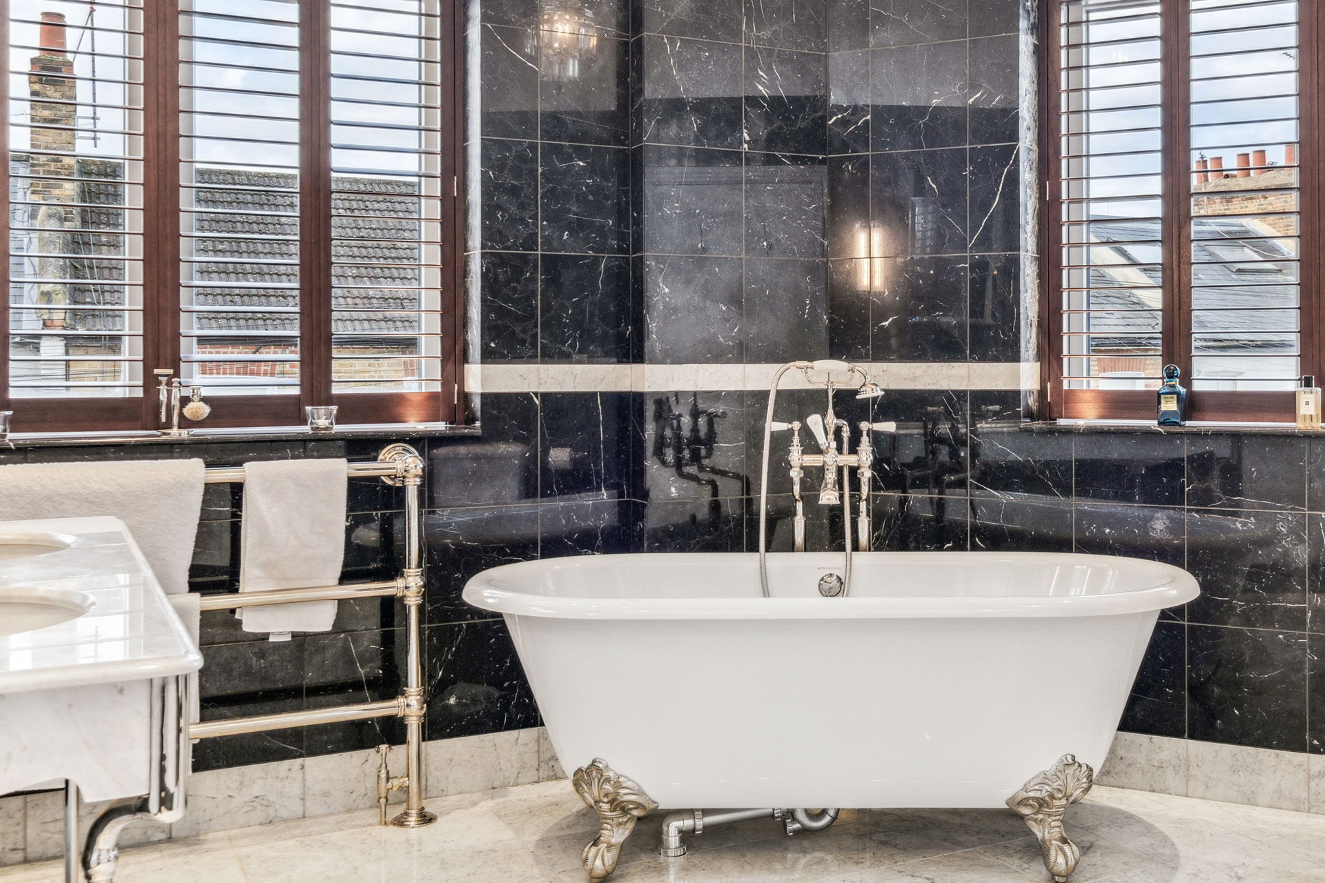 Black marble bathroom with freestanding claw-foot bathtub