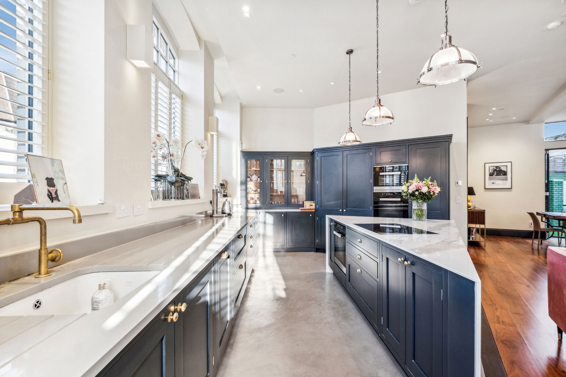Kitchen with navy cabinets, white marble worktops and triangular island