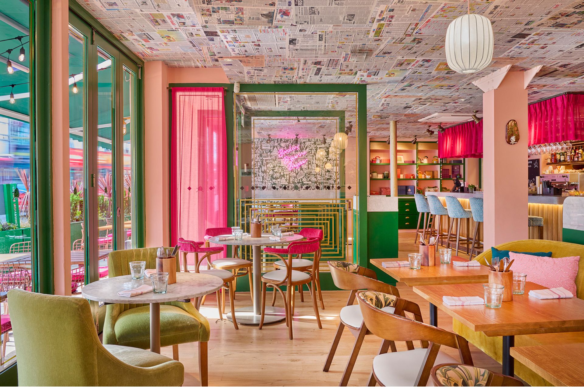 Interiors of Cinnamon Bazaar Richmond, with green velvet dining chairs and pink accents.