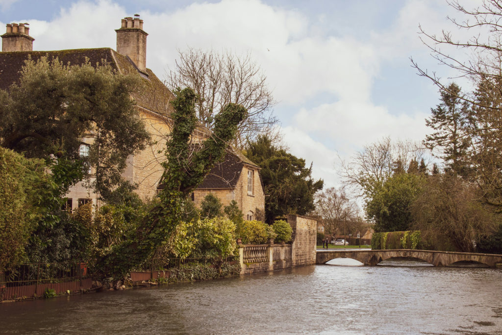 House in Bourton-on-the-Water with a bridge and stream beside it.