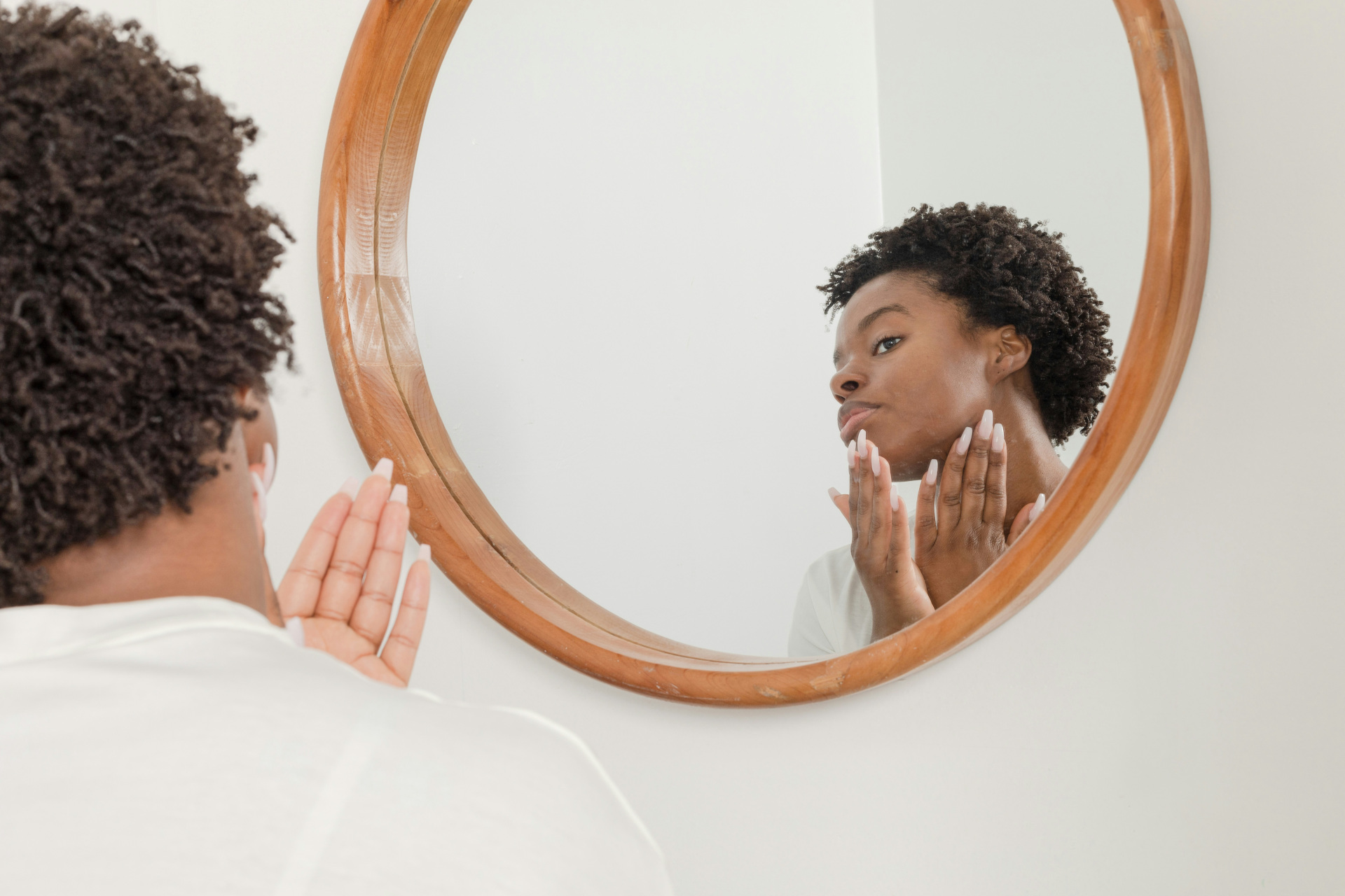 Woman looking in mirror touching face