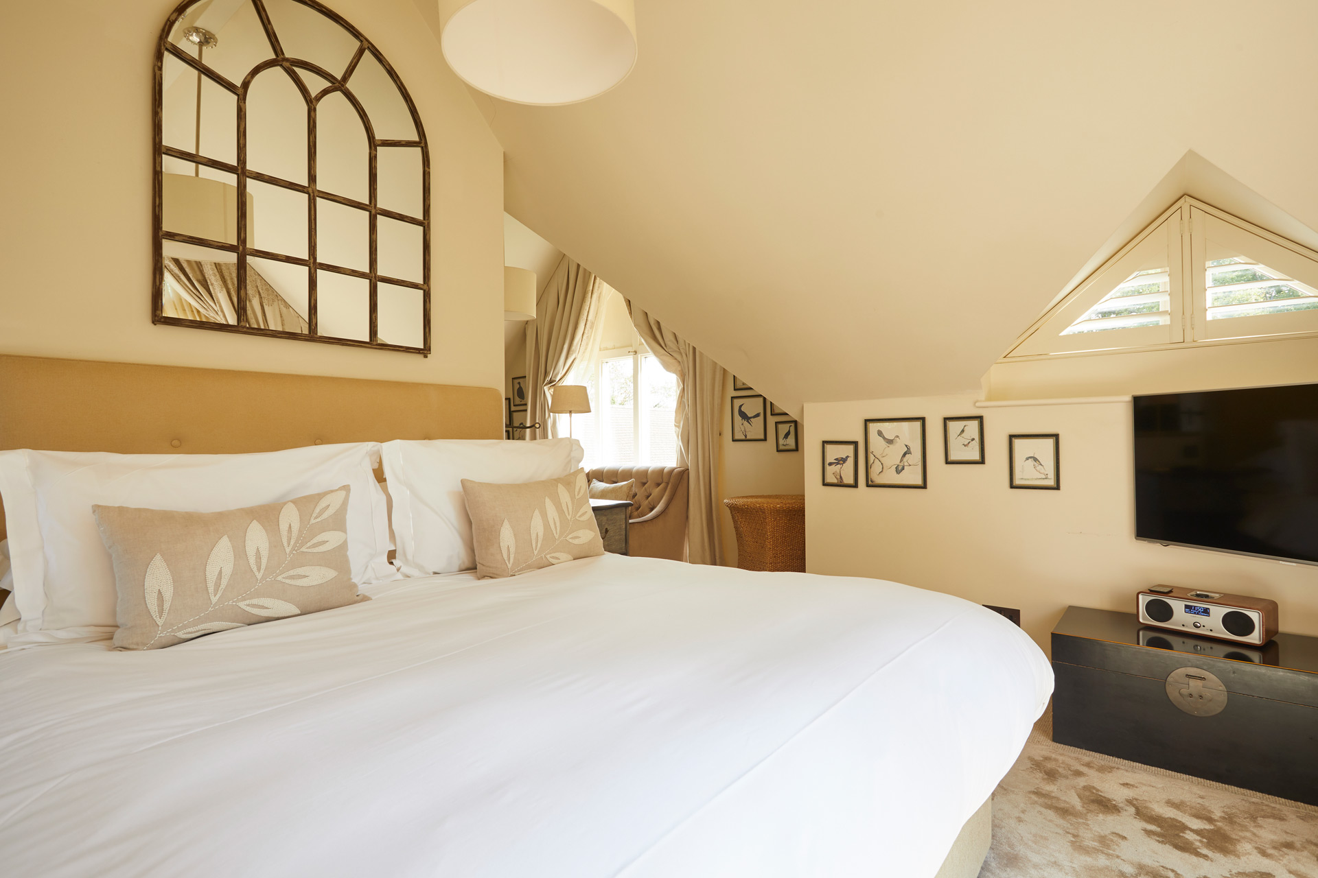 Hotel bedroom with taupe accents and dormer windows.