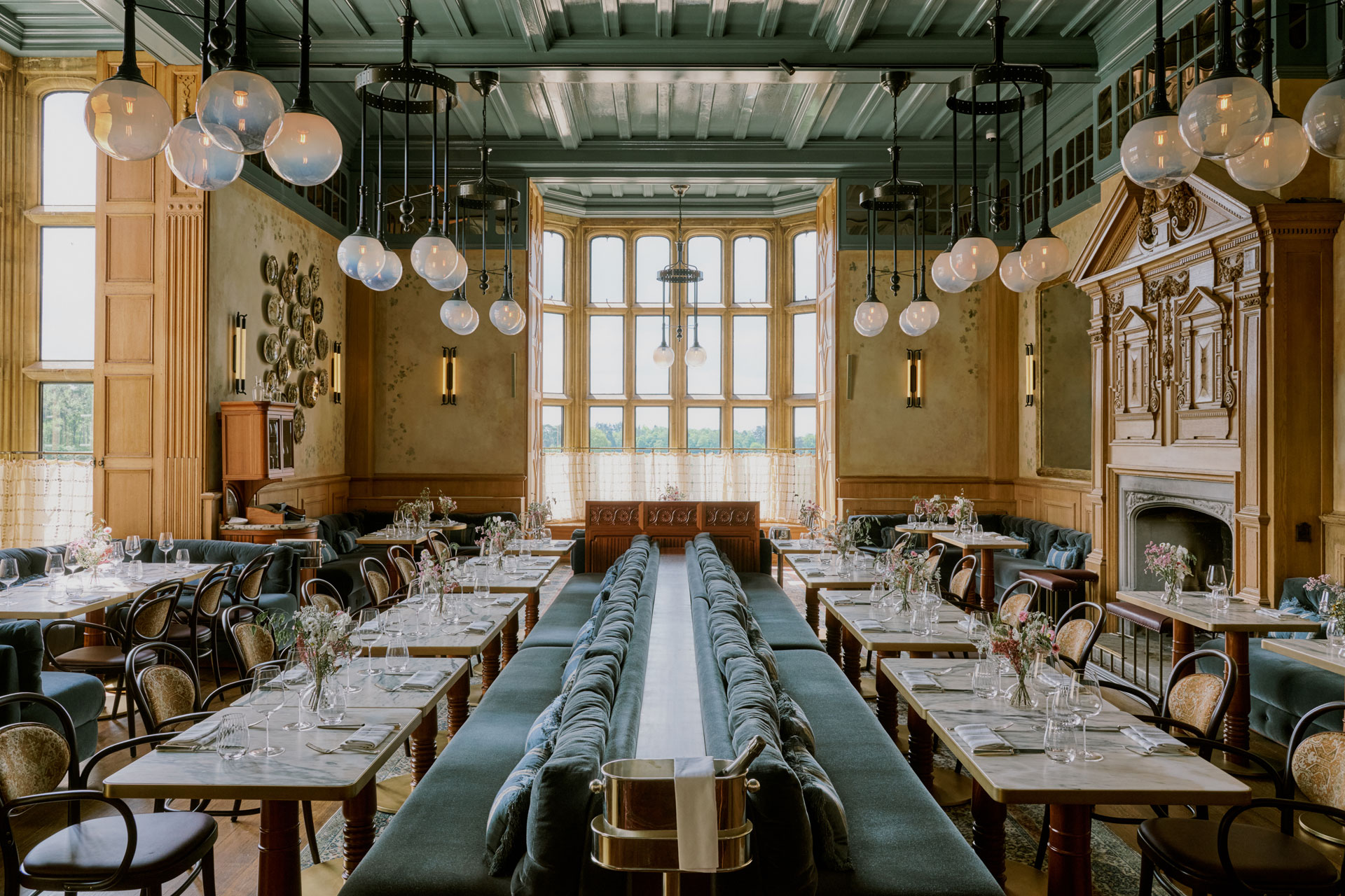 Estelle Manor brasserie with long tables, blue velvet banquettes and circular light pendants.