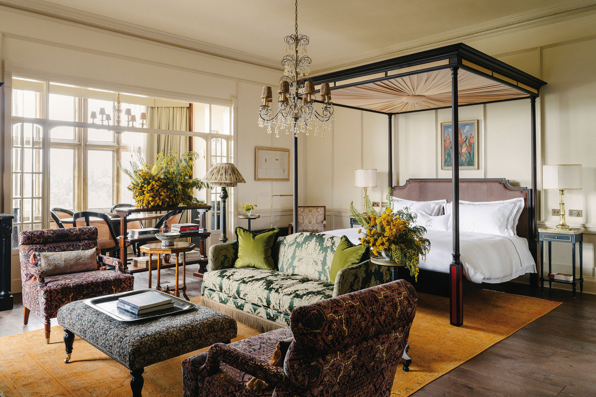 Estelle Manor bedroom featuring a four poster bed, a dining area and red armchairs