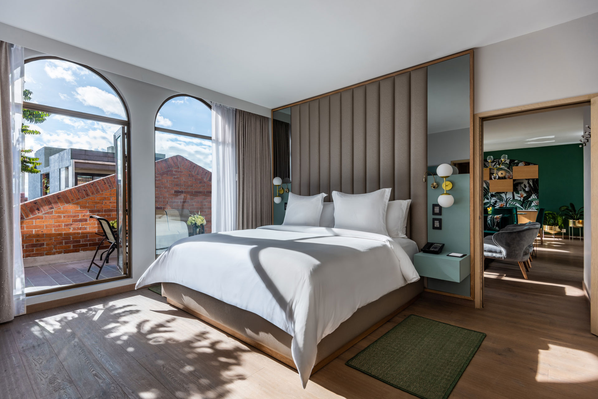 Bedroom with white linens, a brown leather headboard, and arched glass doors leading out to a balcony.