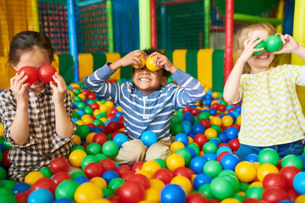 Portrait of three funny little kids playing in ball pit and enjoying time in childrens entertainment and play area
