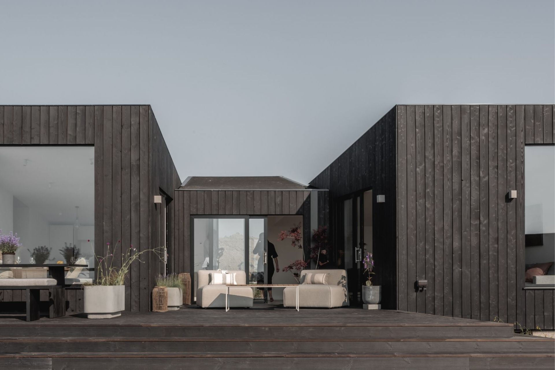 Eco cabin with black wooden cladding and floor to ceiling windows.