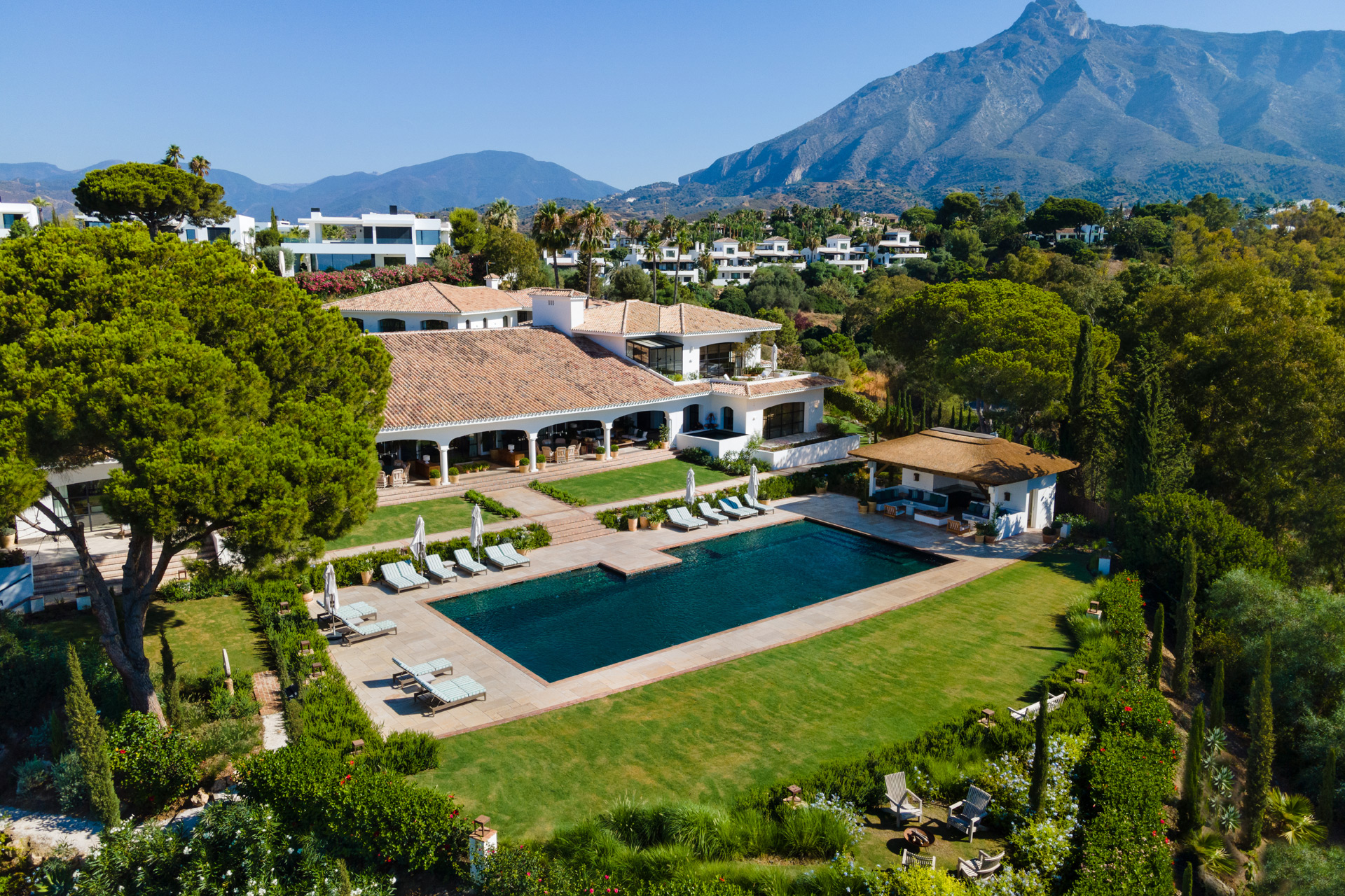 Aerial view of Spanish villa with lawn, pool and covered terrace.