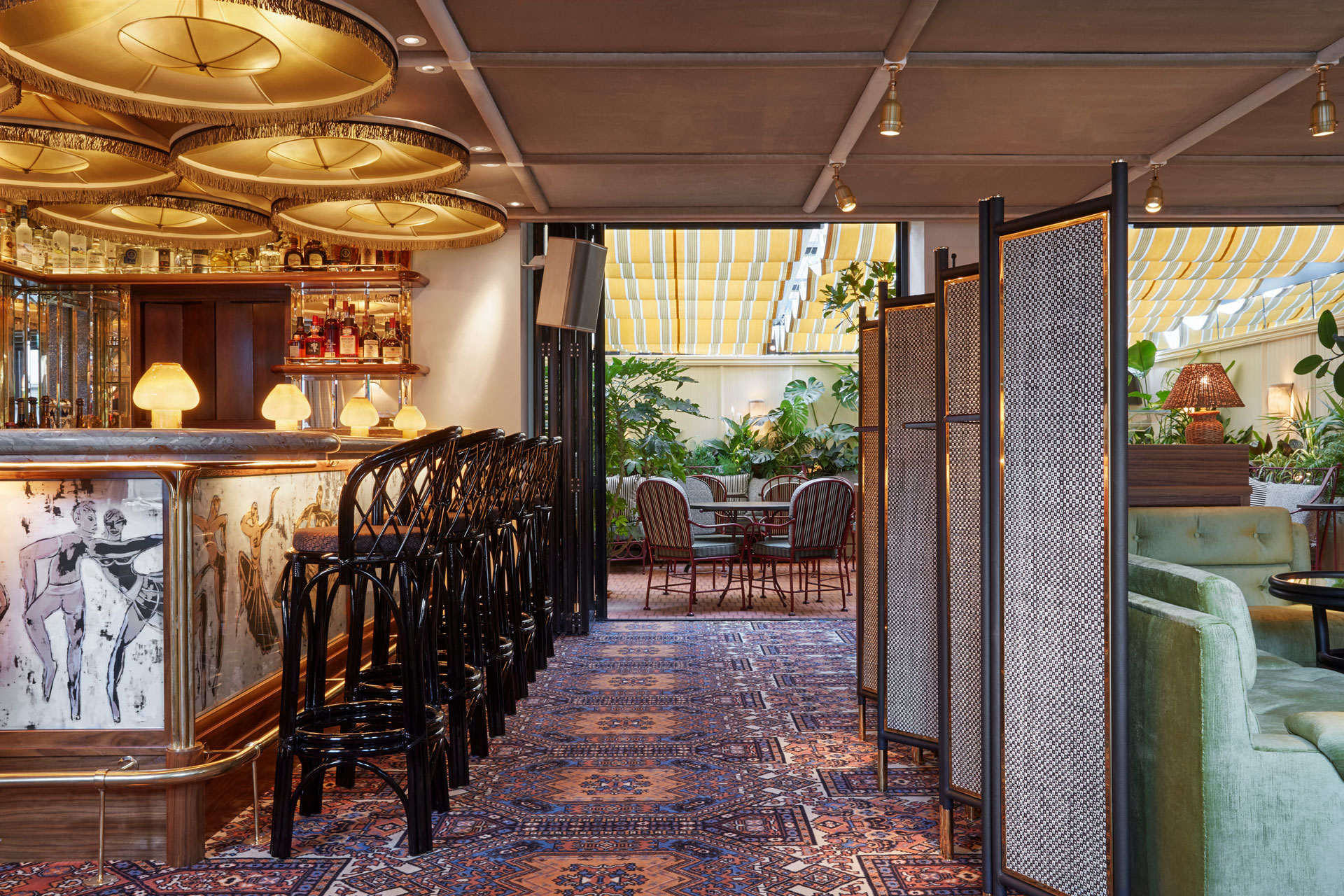 Bar with wooden chairs, Persian rugs and sage green velvet seating