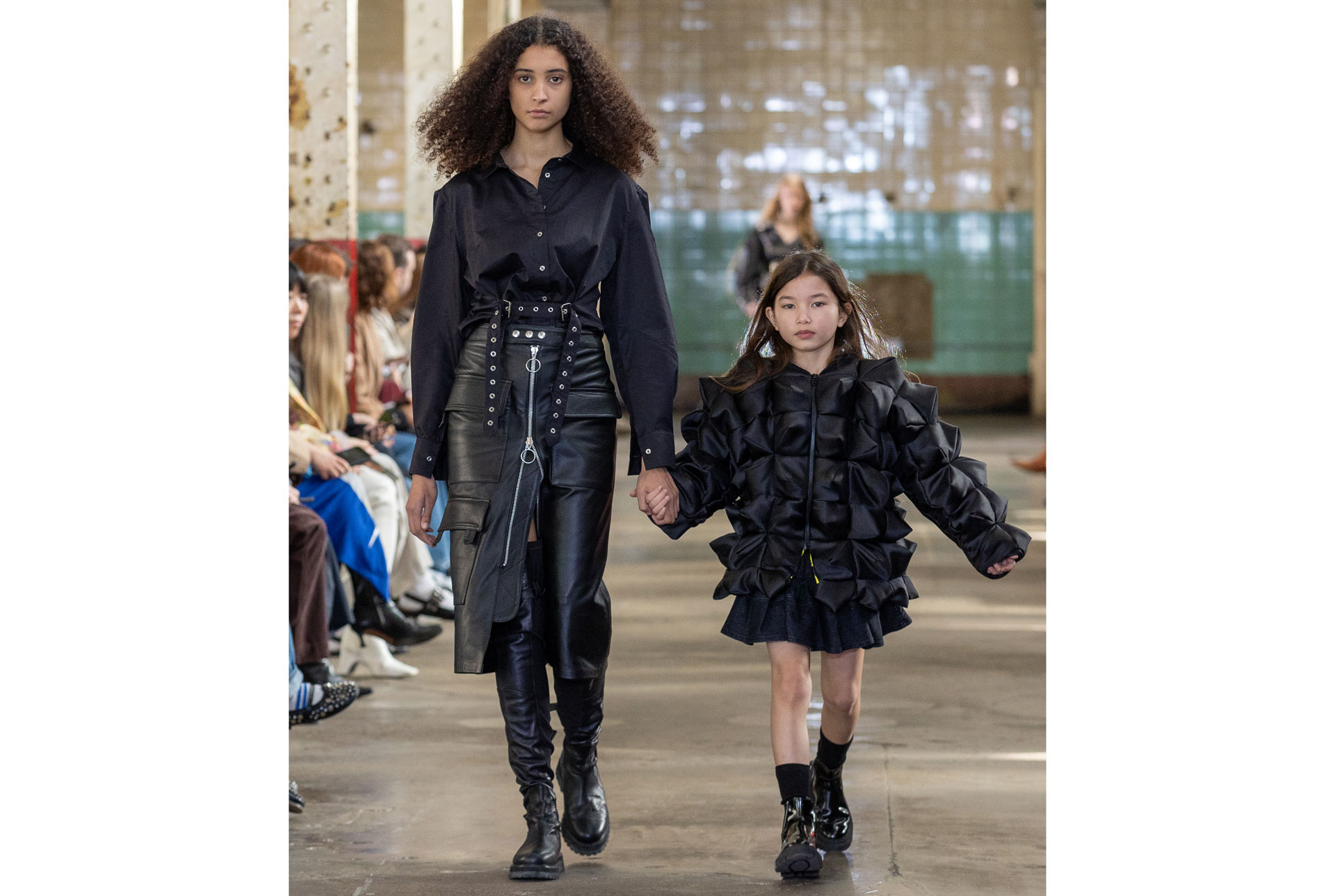 Model and child walking the catwalk in black dresses