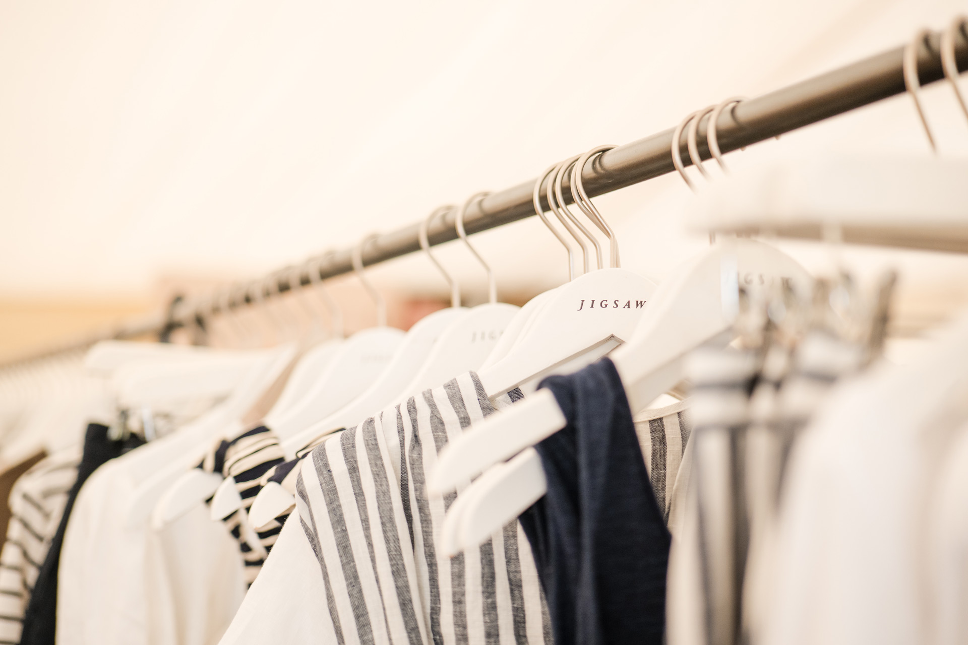 Rows of clothes on white Jigsaw hangers.