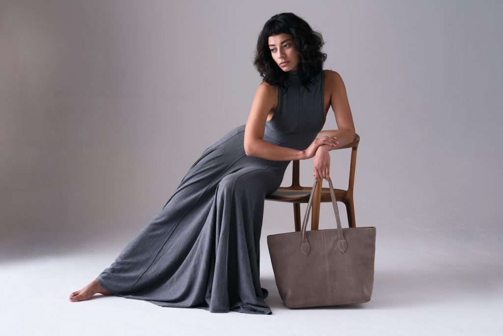 Model in grey dress sitting on chair holding Tusting Alice Collection bag british luxury news march 2024