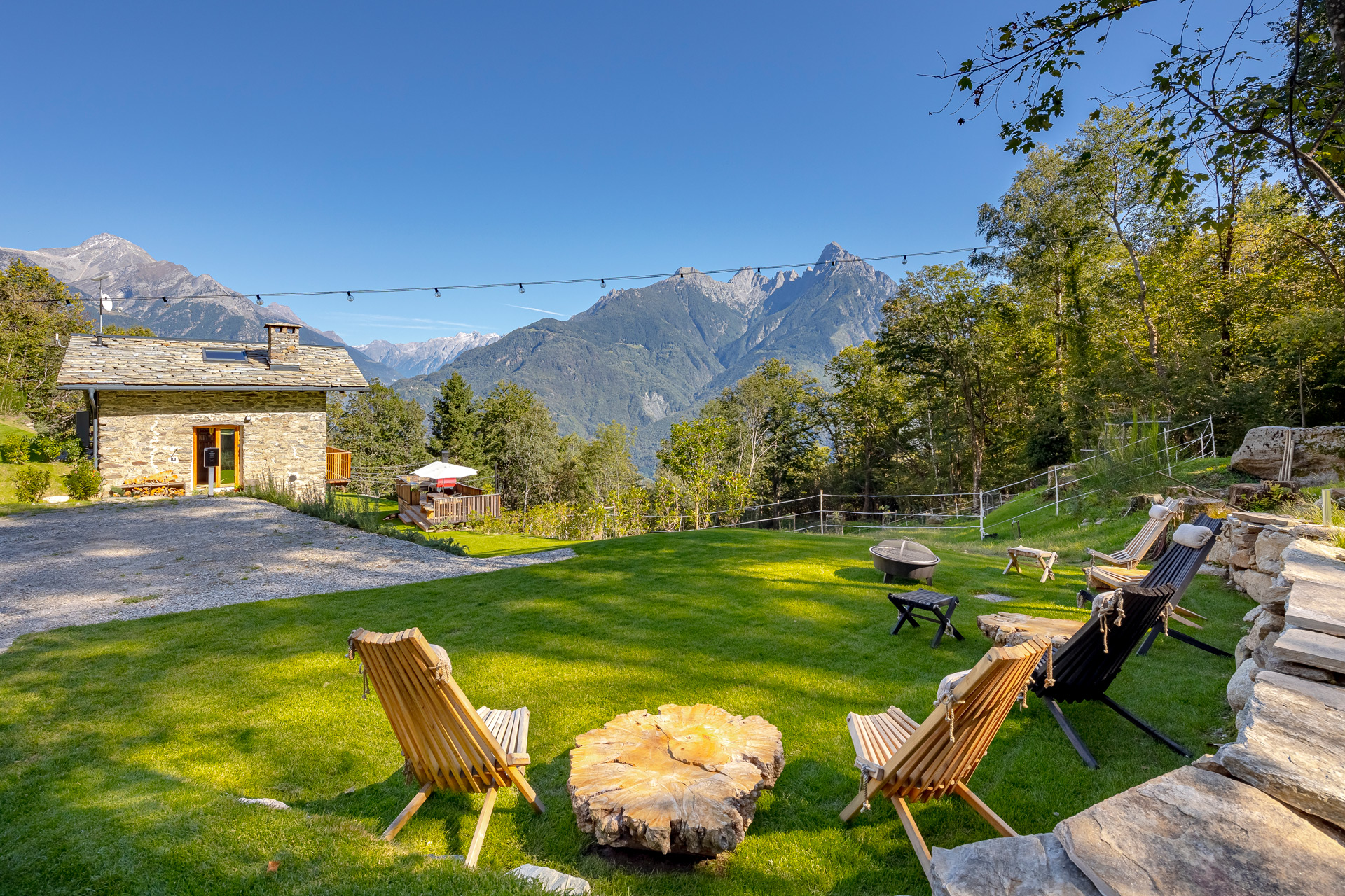 Lawn overlooking the Italian hills, with patio chairs and a stone lodge in the background.