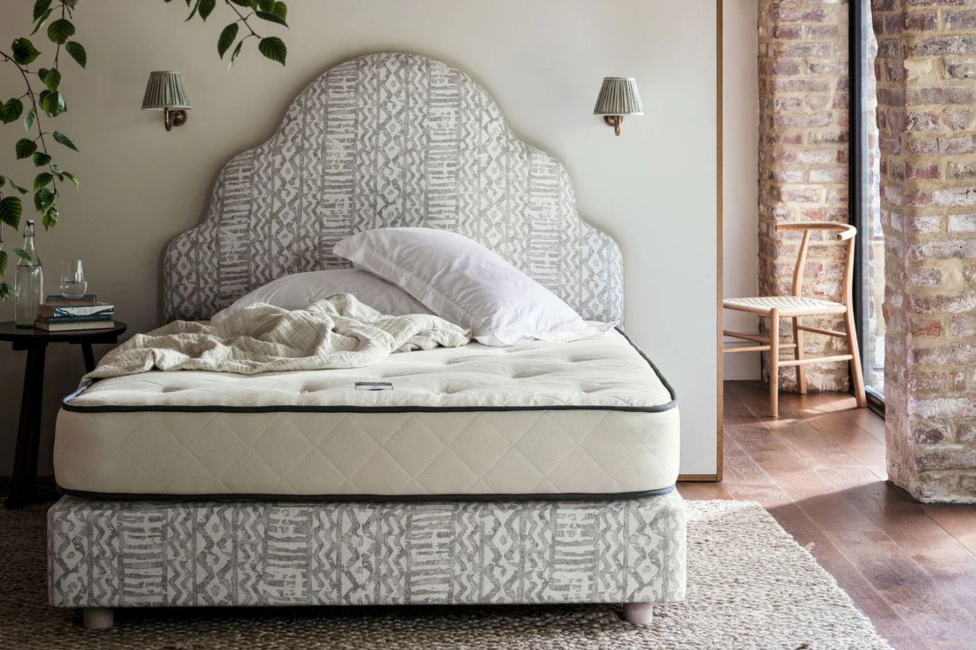 Bed with curved patterned headboard and cream mattress