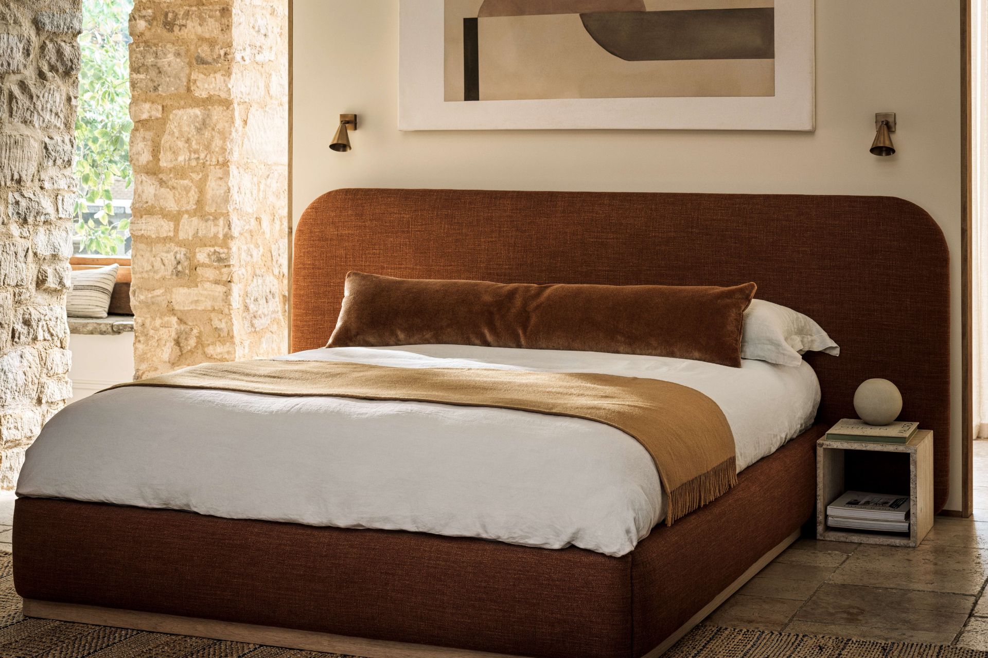 Bed with ochre velvet bedframe, white bedding, and an ochre throw