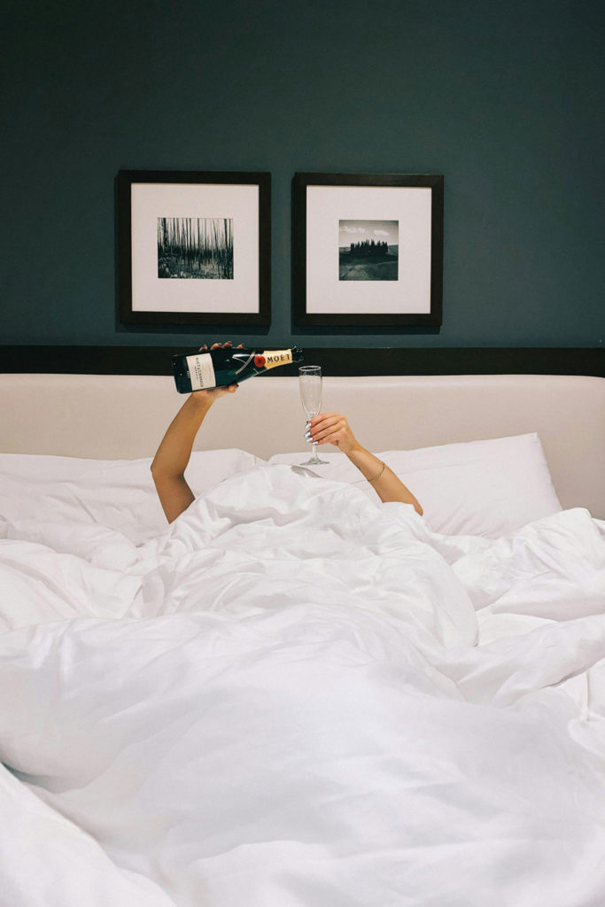 Woman pouring champagne in bed
