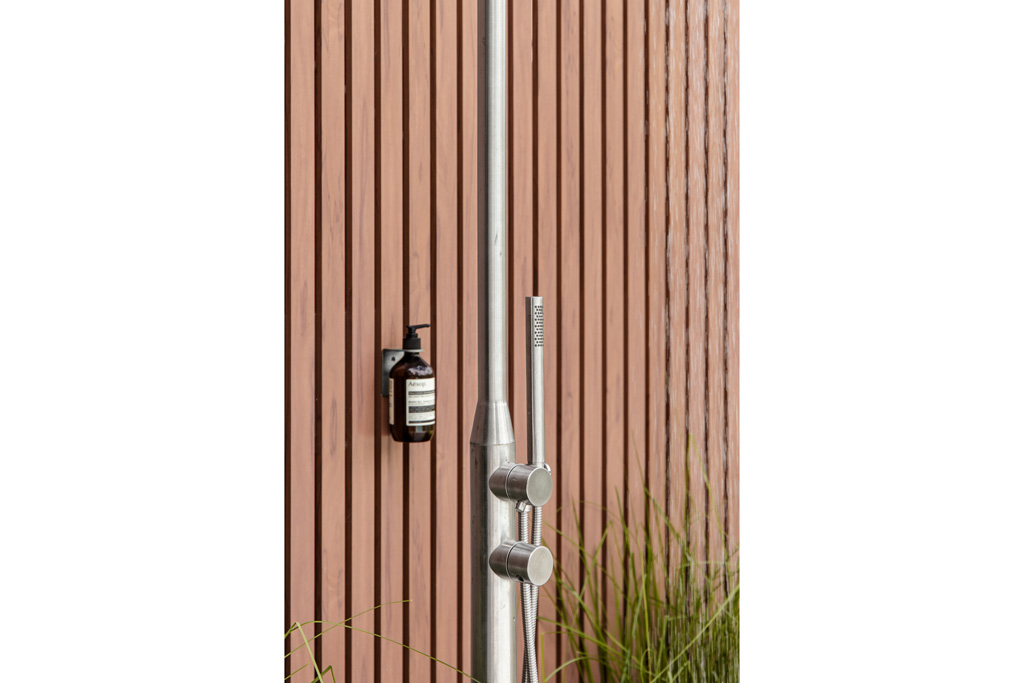 A hand held shower beside soap