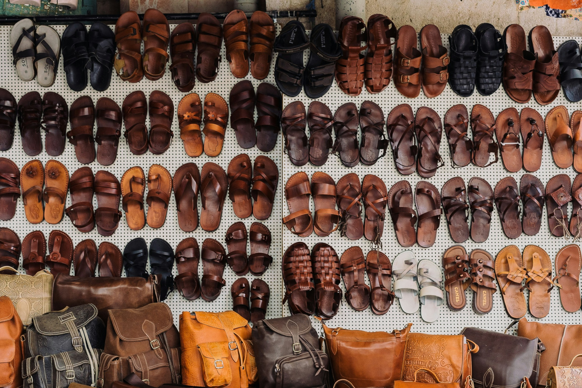 Leather shoes lined up on leather wall over bags
