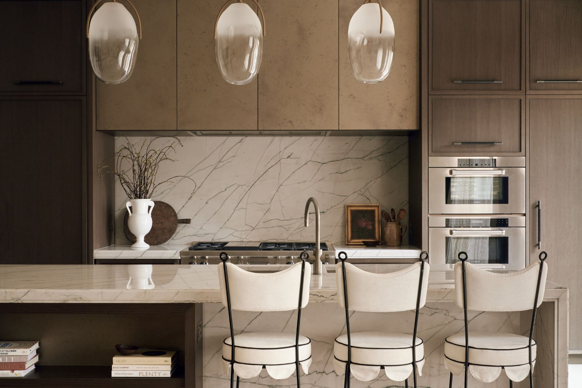 Marble kitchen with white chairs and dark wooden cabinet.