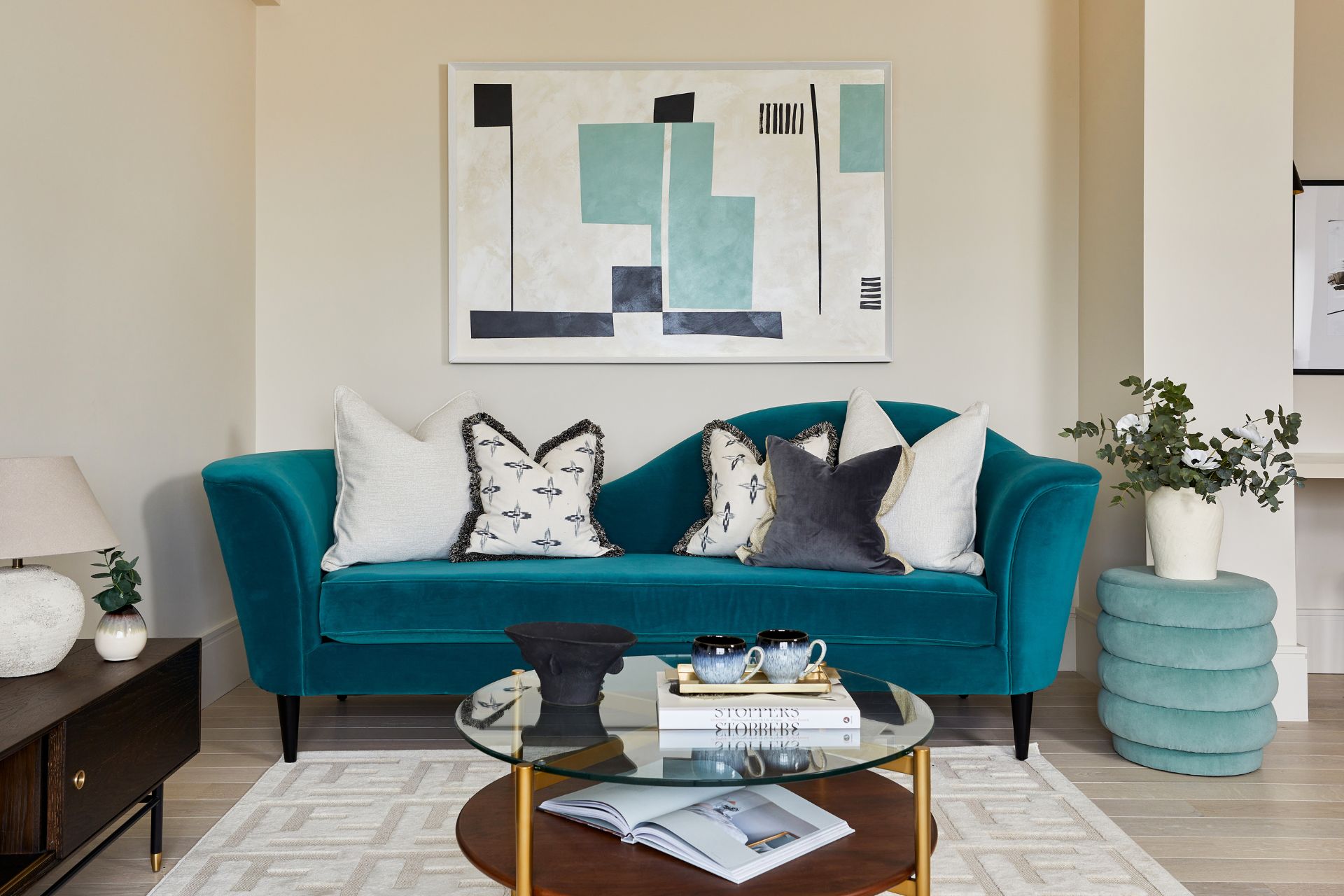 Living room with teal velvet sofa, white and blue patterned cushions and a cream rug.
