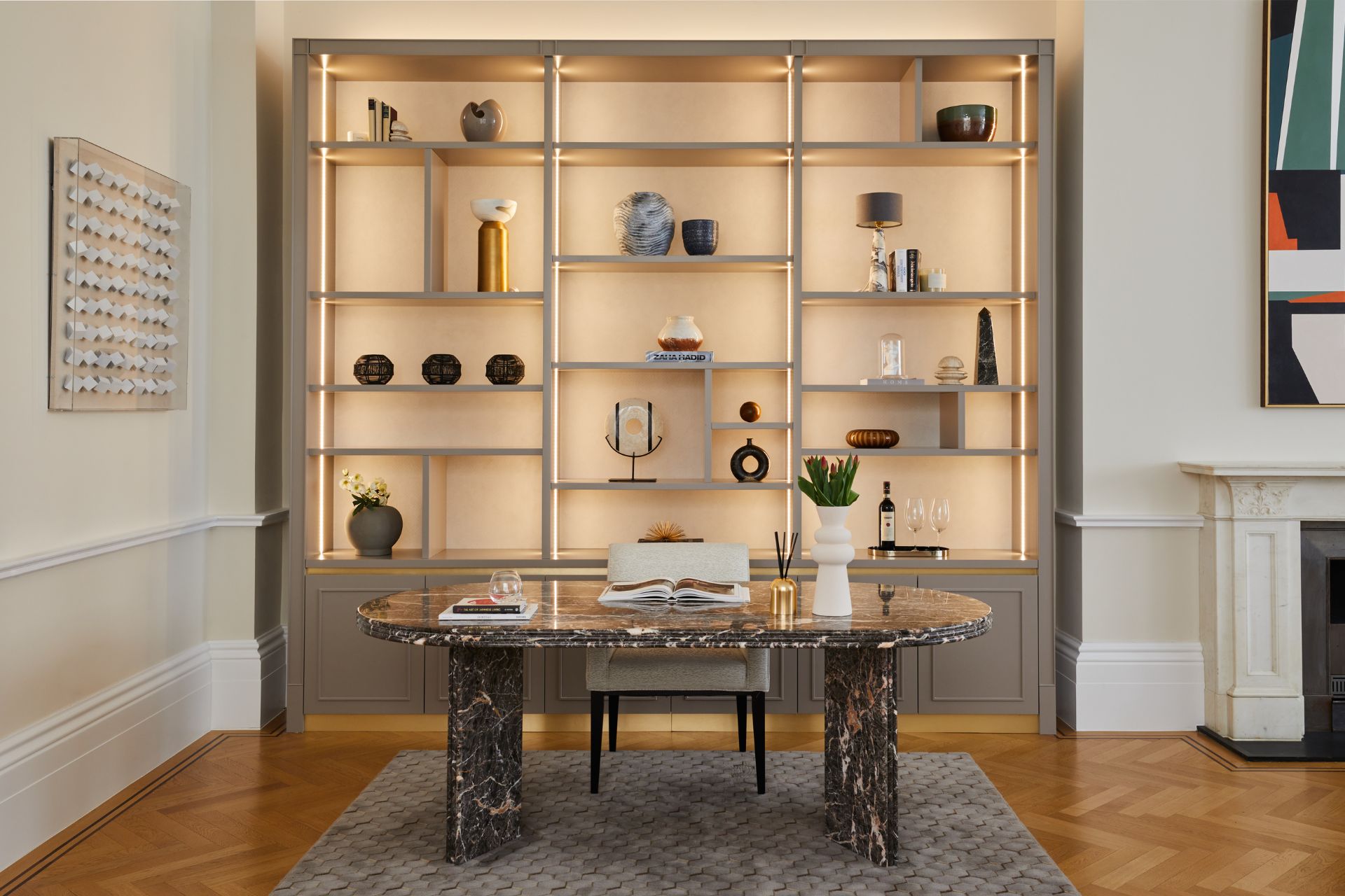 Study with parquet floors, a wooden shelving unit and a marble desk.