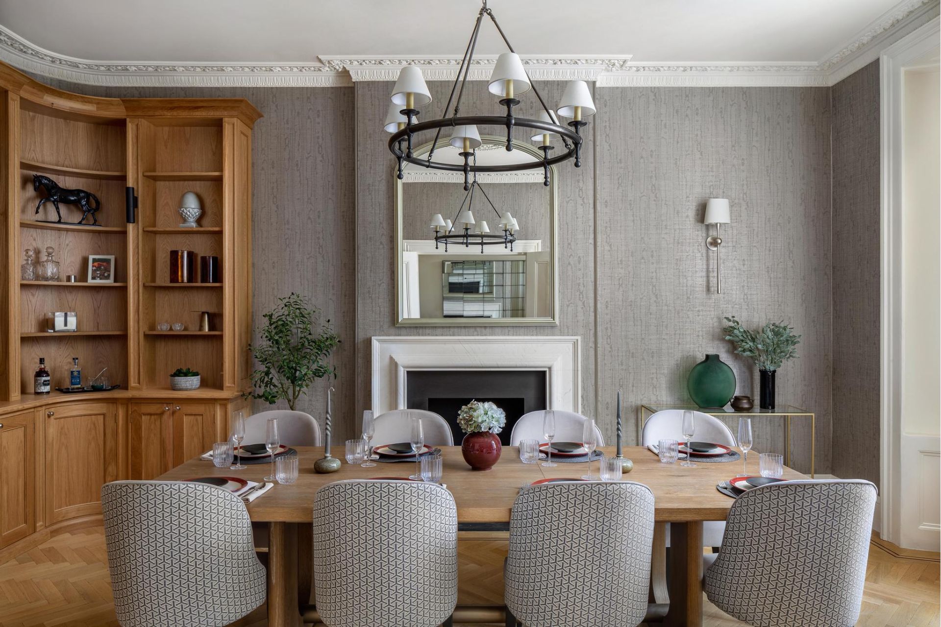 Dining room with grey walls and chairs and an oak shelving unit.