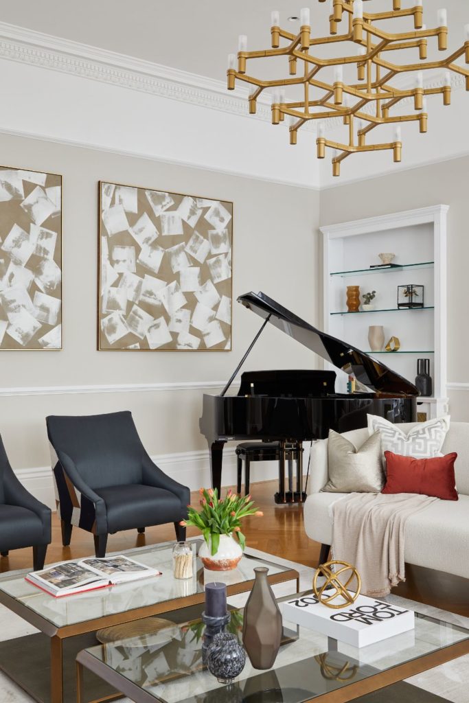 Living room with gold chandelier, grand piano and navy armchairs.