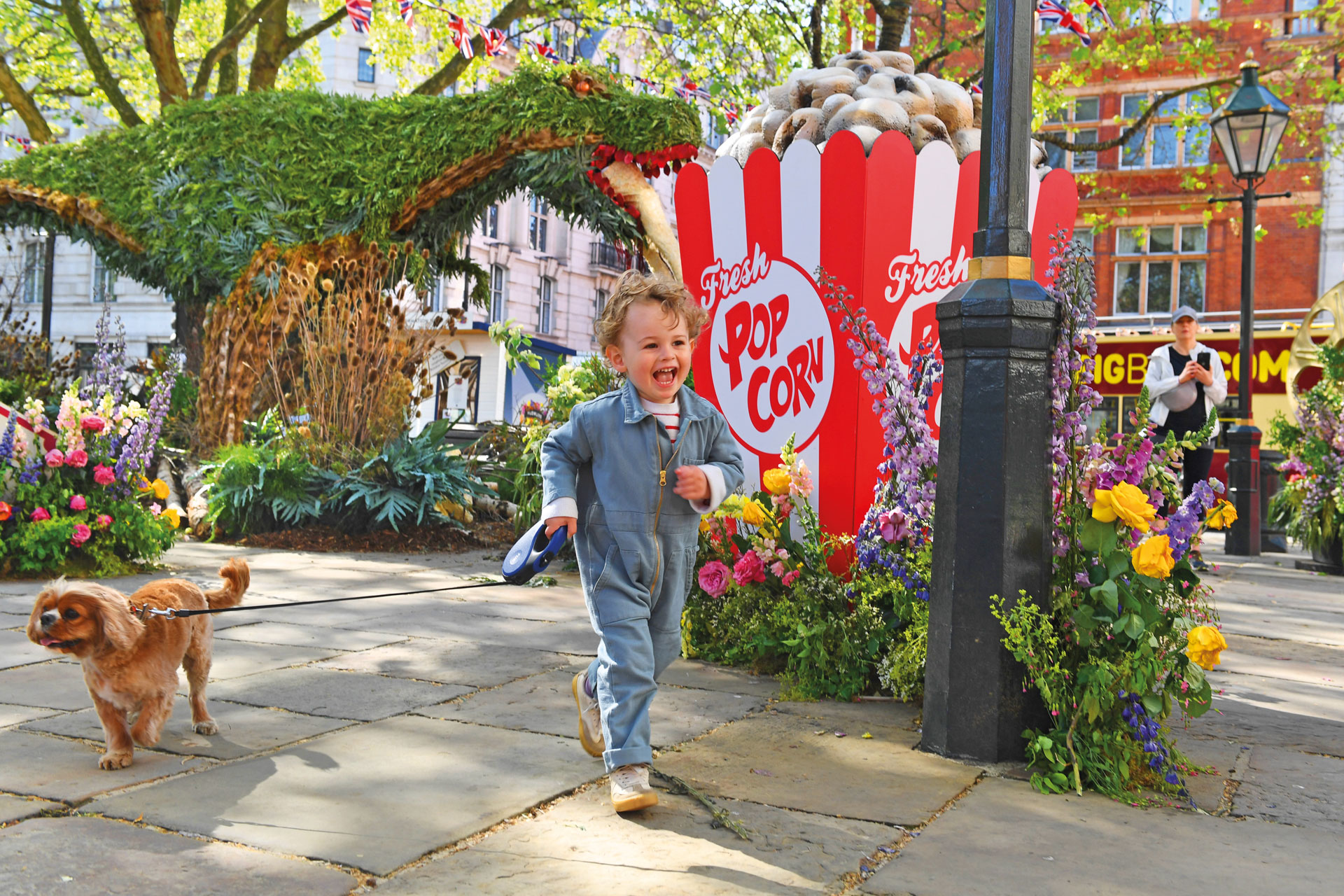 Chelsea In Bloom: child runnng away from a hedge cut like a dinosaur