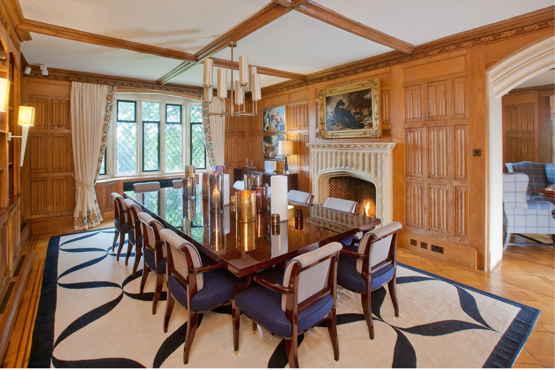 Wood panelled dining room with navy chairs and a cream and navy patterned rug.