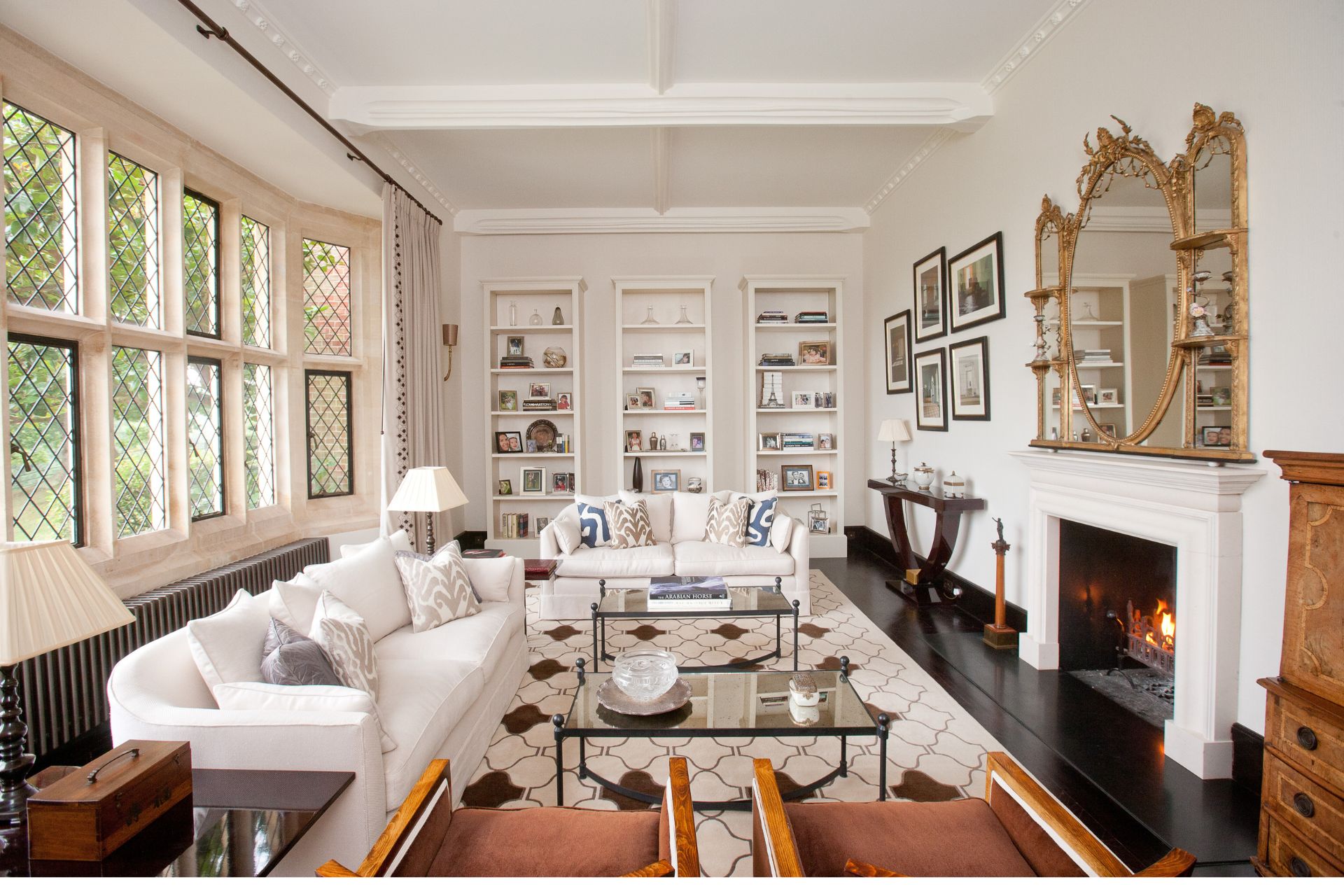 Living room with cream sofas, a marble fireplace and white bookshelves.