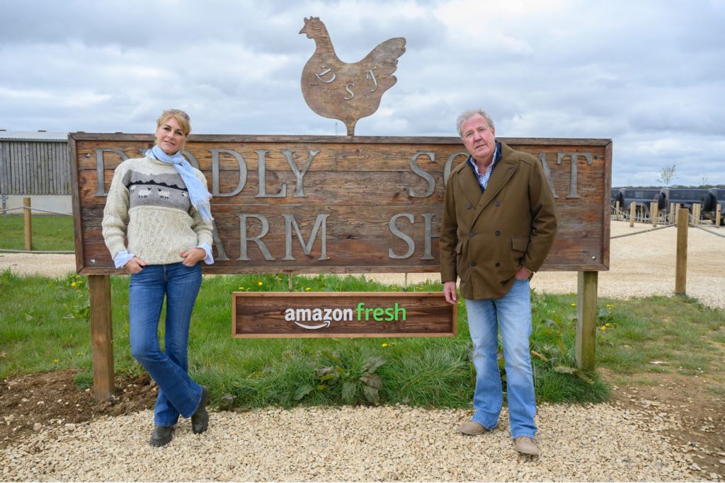 Lisa Hogan and Jeremy Clarkson standing in front of the Diddly Squat Farm sign.