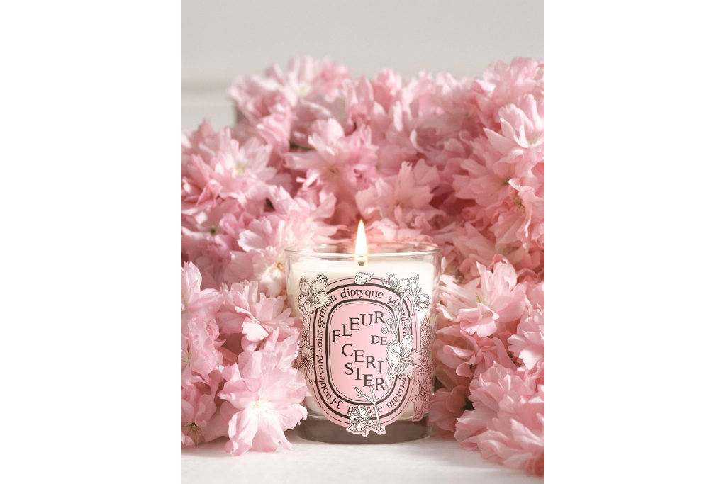 Glass candle in front of pink flowers