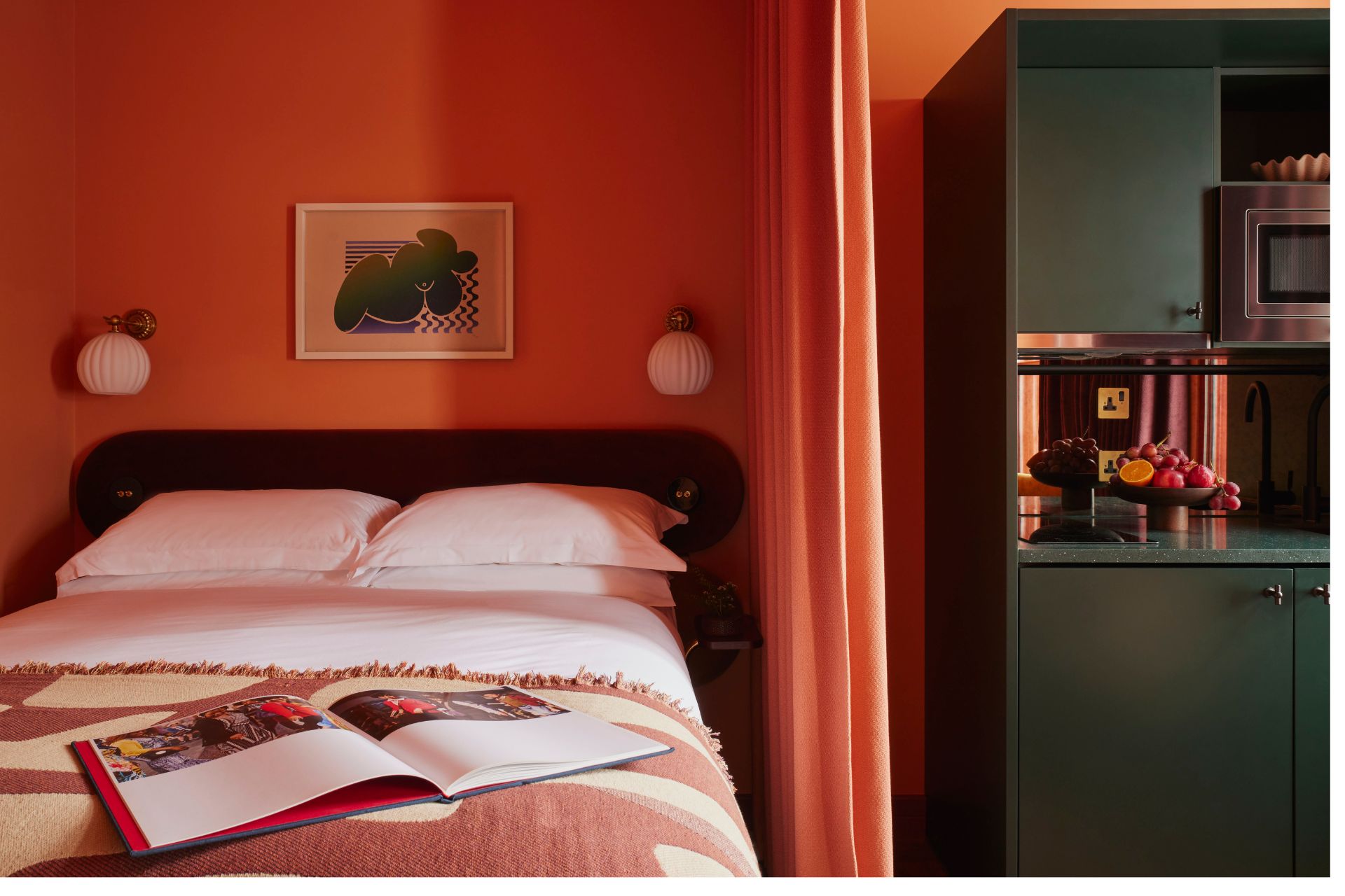 Bedroom with red walls, white linens and dark green cabinets.