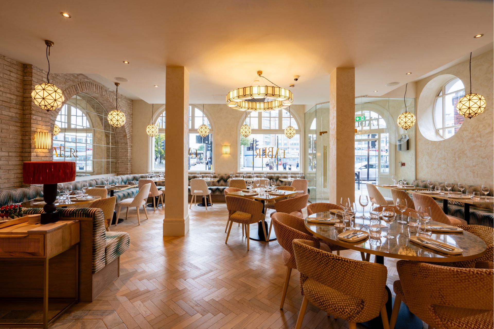 Restaurant interior with parquet floors, art deco lampshades and white and gold chairs.