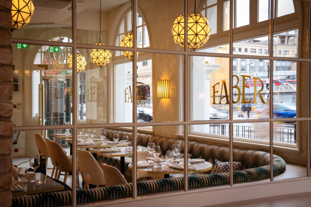 Restaurant interior featuring Art Deco lampshades and patterned banquettes.