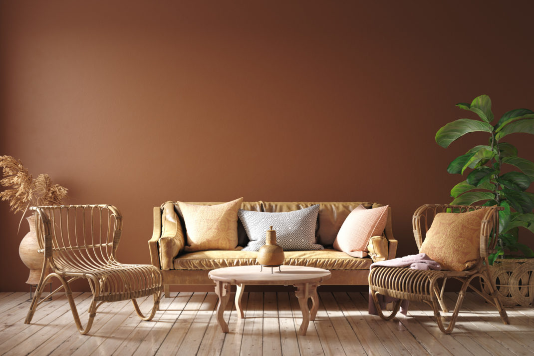 Modern interior in terracotta color with leather sofa, rattan armchairs and flower, 3d render