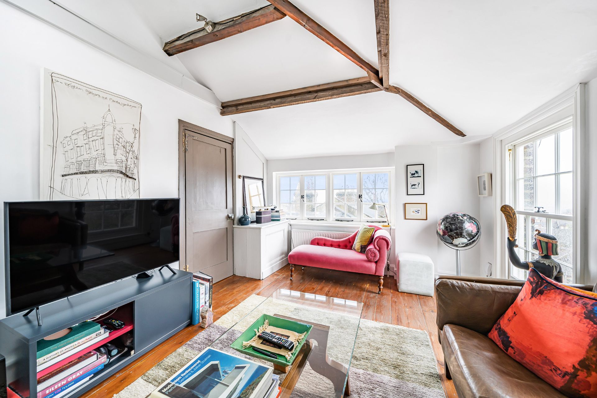 Hampstead home with wooden ceiling beams and red sofas.