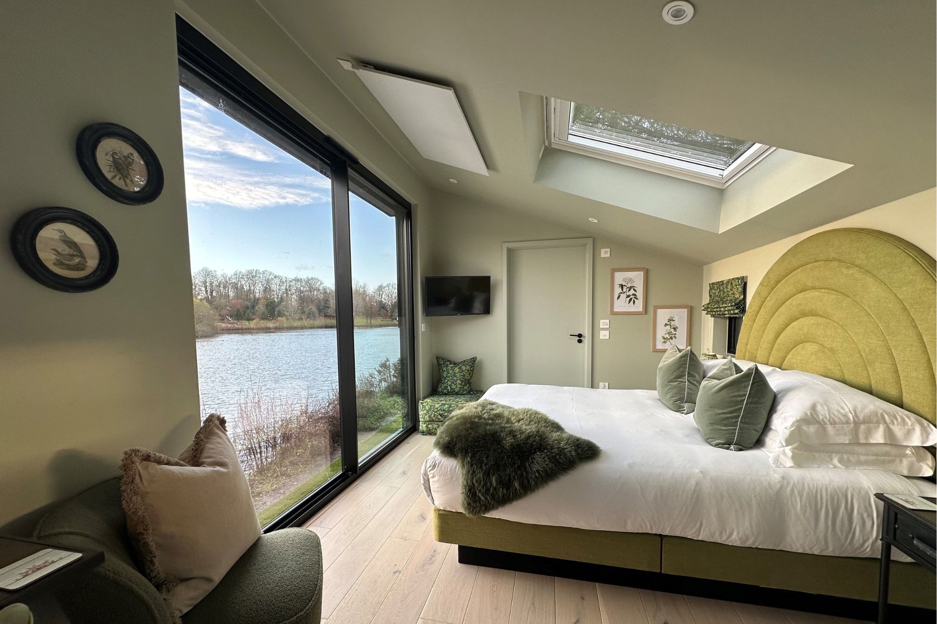 Leeds Castle lodge bedroom with green headboard and floor-to-ceiling windows overlooking the lake.