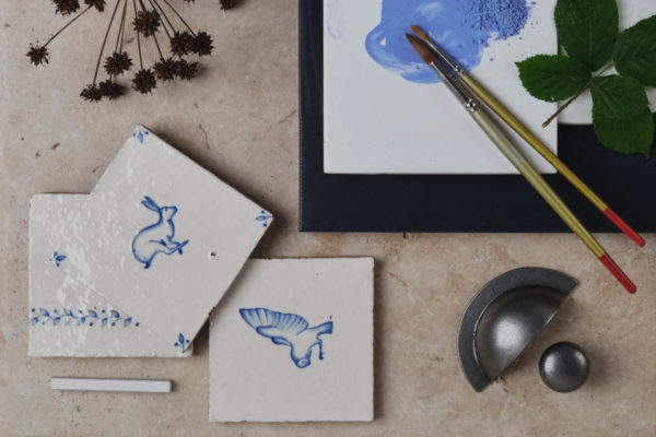 Blue and white illustrated tiles next to paint brush
