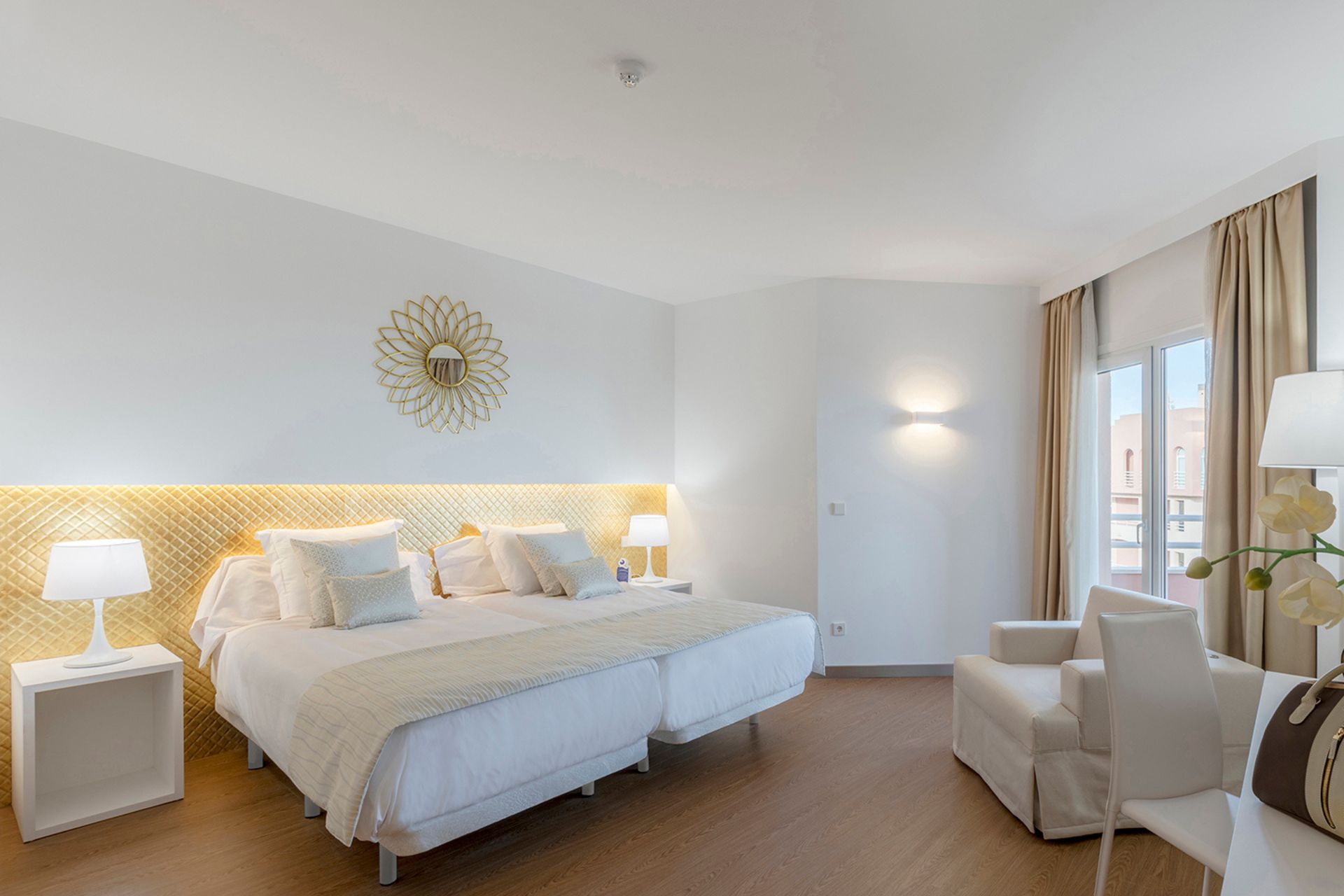 Hotel bedroom with white linens, white walls and cream accents.